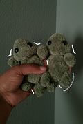 A small plush toy turtles. The turtles are olive green with black bead eyes and brown shell on their backs.