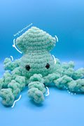 A crocheted plush octopus toy in mint green with black bead eyes.