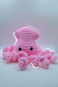 A pink crocheted octopus plush toy with black bead eyes.