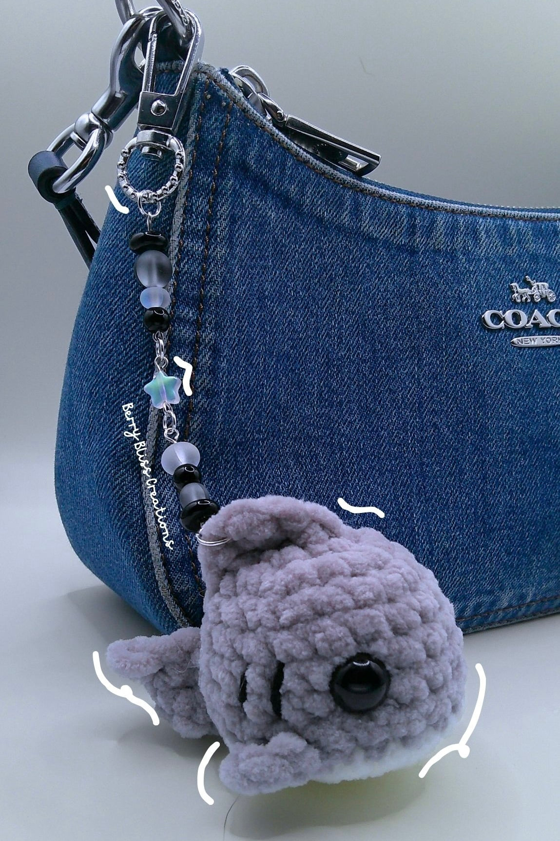 A small gray crocheted whale plush, (Coach bag not included)